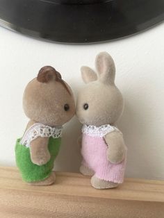 two stuffed animals sitting on top of a wooden shelf