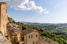 an aerial view of some buildings and trees in the distance with mountains in the background