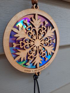 a wooden snowflake ornament hanging from a door with a black cord