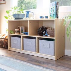 a wooden shelf with baskets and plants on it in a room next to a window