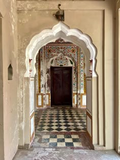 the entrance to an ornate building with tiled floors and arches, painted in multicolors