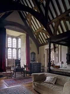 an old fashioned bedroom with large windows and wooden beams on the ceiling is furnished with antique furniture