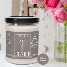 a candle next to a vase with pink flowers in it and the label on top