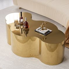 a gold coffee table with two bottles on it and a couch in the back ground