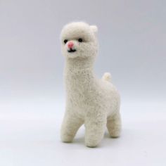 a small white stuffed llama standing on a plain surface with its eyes closed and tongue out