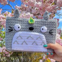 a person holding up a crocheted wallet with an animal face on the front