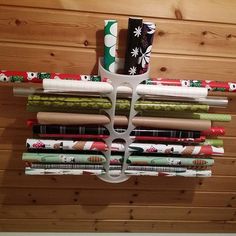 several rolls of wrapping paper are hanging on a wooden wall with a metal holder holding them