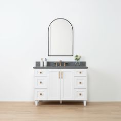 a white bathroom vanity with a mirror and two faucets on the counter top