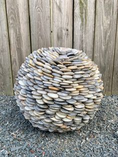 a stone ball sitting on top of gravel next to a wooden fence