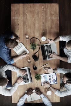 four people sitting at a table with laptops and papers in their hands - stock photo - images