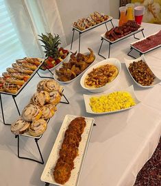 an assortment of food is displayed on a long table with white linens and fruit