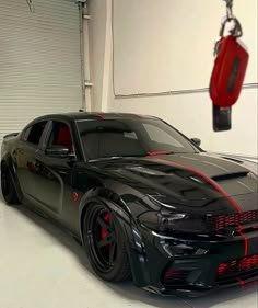 a black car with red stripes parked in a garage next to a pair of scissors