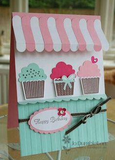 a handmade card with cupcakes on the front and sides, attached to a pair of scissors