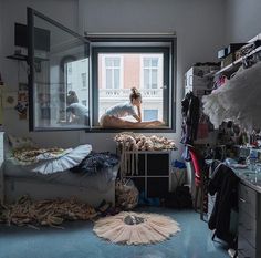 a woman sitting on top of a bed in a bedroom next to a large window