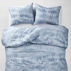 a blue and white bed with two pillows on top of the pillowcase, next to a wall