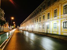 an empty city street at night with lights on the buildings and water running down it