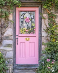 a pink door with a stained glass rose in the center and ivy growing around it