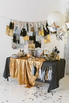 a black and gold birthday party with balloons, streamers and confetti on the table