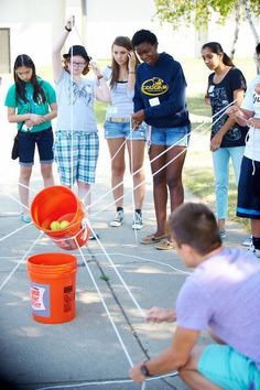 a group of young people standing around an orange bucket