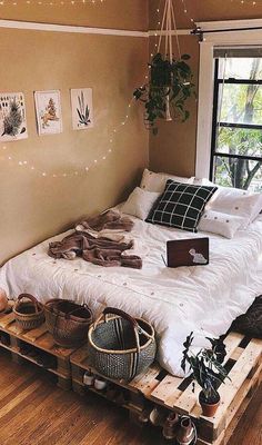 a bed sitting on top of a wooden pallet in a bedroom next to a window