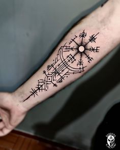 a man's arm with a compass tattoo on the left side of his arm