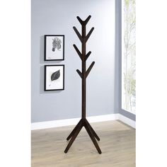 a wooden coat stand with three pictures on the wall and one tree in the corner