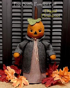 a stuffed pumpkin dressed in a coat and tie with leaves around it on the ground