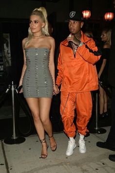 two people standing next to each other wearing orange outfits