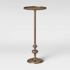 a tall brass candle holder with two candles on it's sides and a white background