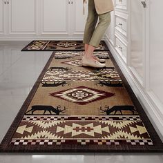 a woman standing on a rug in the middle of a room with white cupboards