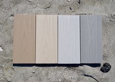 four different colors of wood sitting in the sand