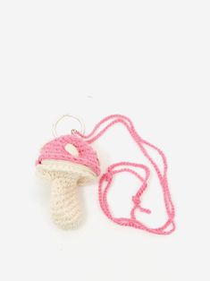 a crocheted mushroom ornament is shown on a white surface with a pink cord