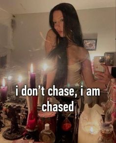 a woman standing in front of a table with candles on it and the caption i don't chase, i am chased