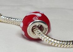 a red and white bead on a silver plated metal cord with the word hello kitty written on it