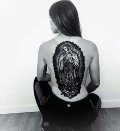 a woman sitting on the floor with her back to the camera and tattoos on her body