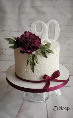 a white cake with purple flowers on top and the number 90 on it's side