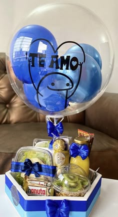 a blue box filled with balloons and other items sitting on top of a white table