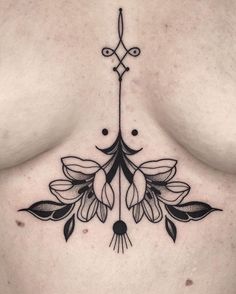 a woman's chest with tattoos on it and flowers in the middle, as well as an arrow