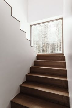 a set of stairs leading up to a window in a house with white walls and wood floors