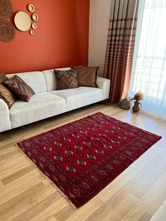 a living room with a white couch and red rug on top of the wooden floor