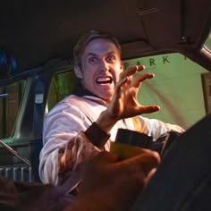 a man in the back seat of a car with his hands out and mouth wide open