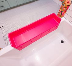 a pink plastic shelf sitting on top of a white bath tub