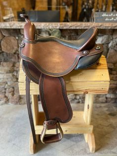 a brown saddle sitting on top of a wooden bench