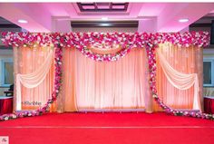 the stage is decorated with pink flowers and white drapes for an elegant wedding ceremony