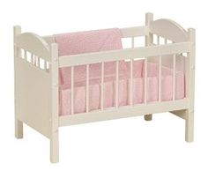 a white crib with pink bedding on the bottom and side rails, for dolls