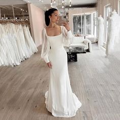 a woman standing in front of a white wedding dress