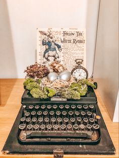 an old fashioned typewriter sitting on top of a wooden table next to a book