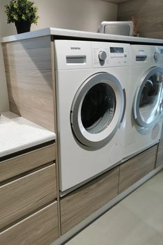 a washer and dryer sitting on top of a counter in a room with wooden cabinets