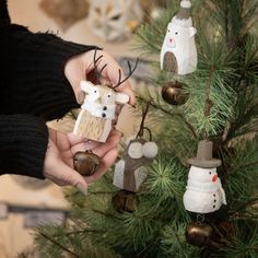 a person holding an ornament in front of a christmas tree with other ornaments