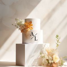 a three tiered wedding cake with flowers on the top and initials on the side